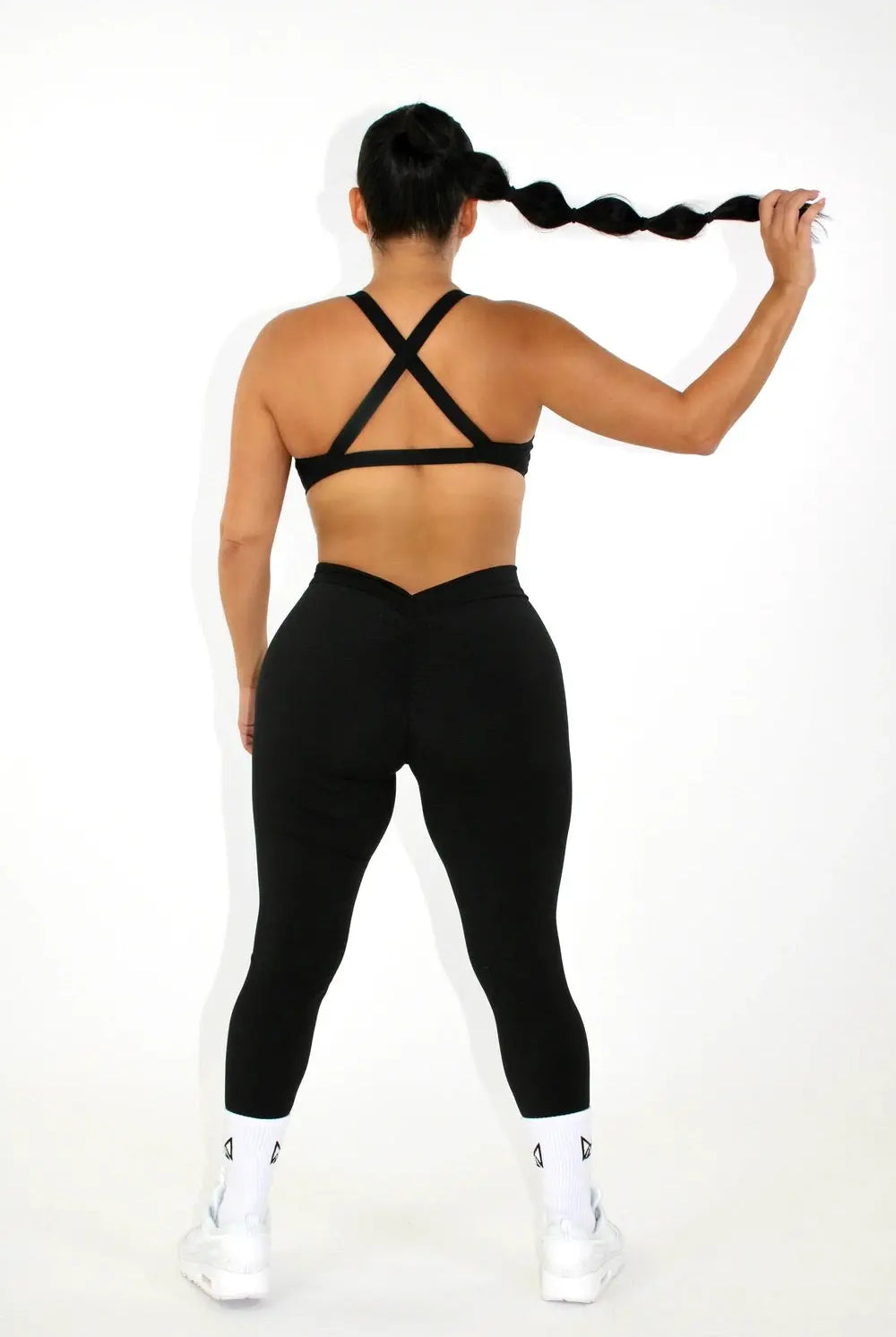 Woman wearing black leggings and a black sports bra - back