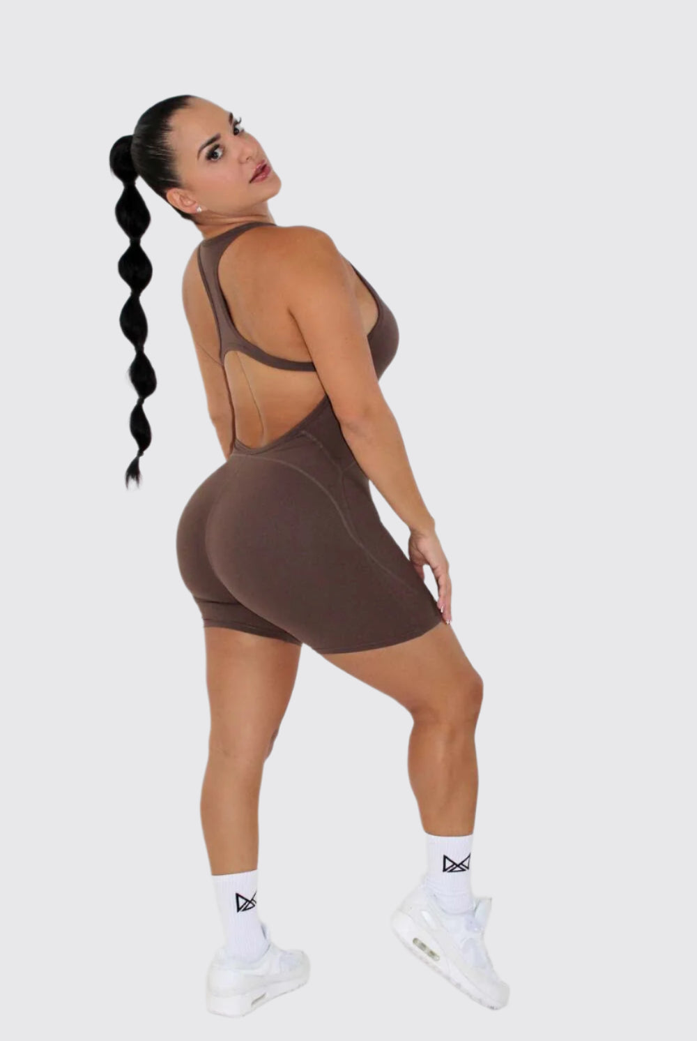 Women wearing a black MILA MVMT Sportswear One-Piece Gym Workout Romper Onesie - facing side looking at the camera