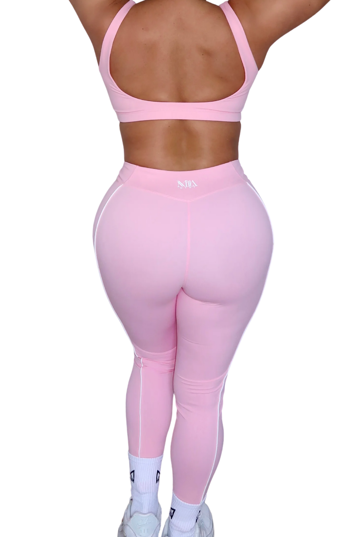 Back view of woman wearing petal pink leggings by MILA MVMT