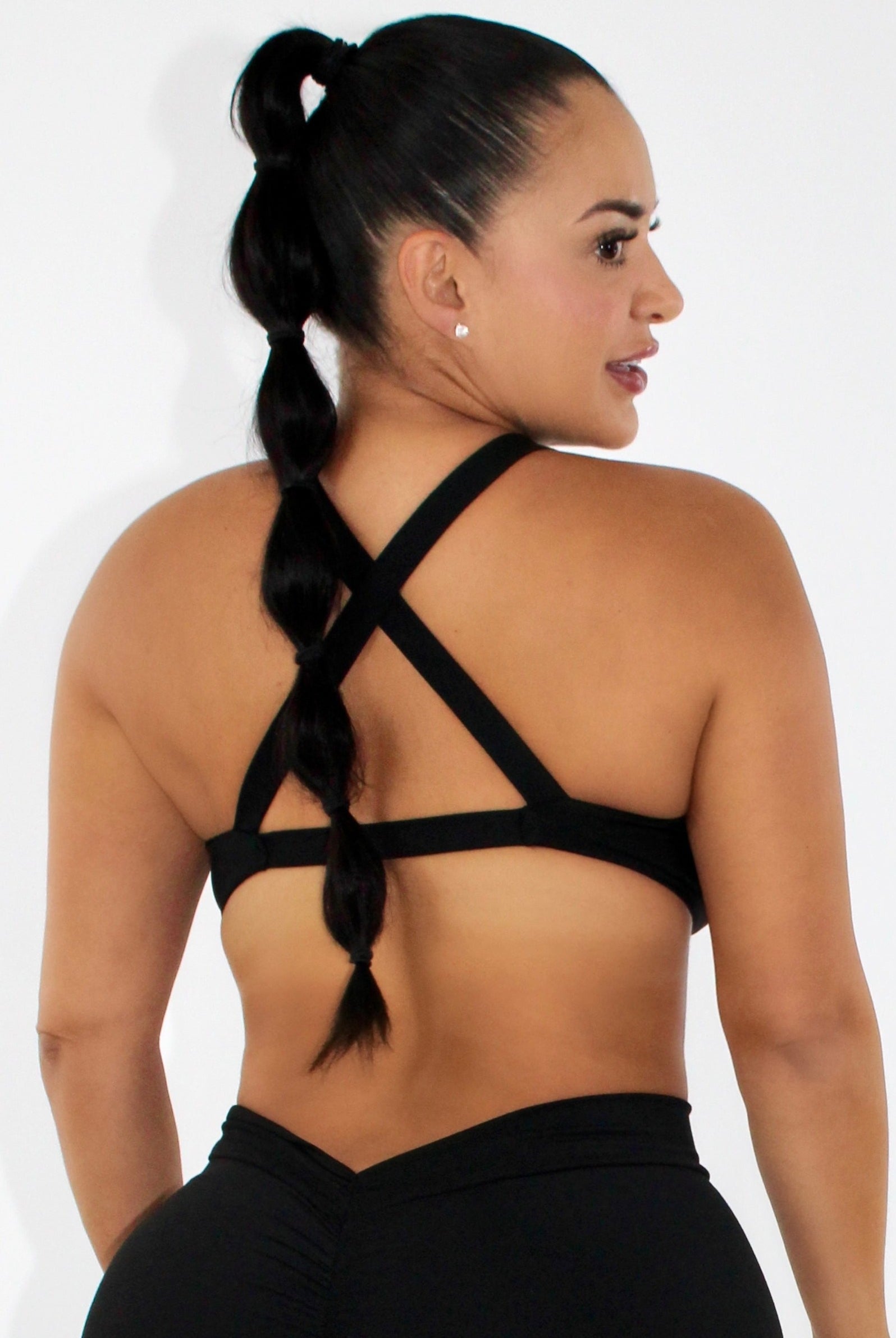 Woman wearing black leggings and a black sports bra - showing back side