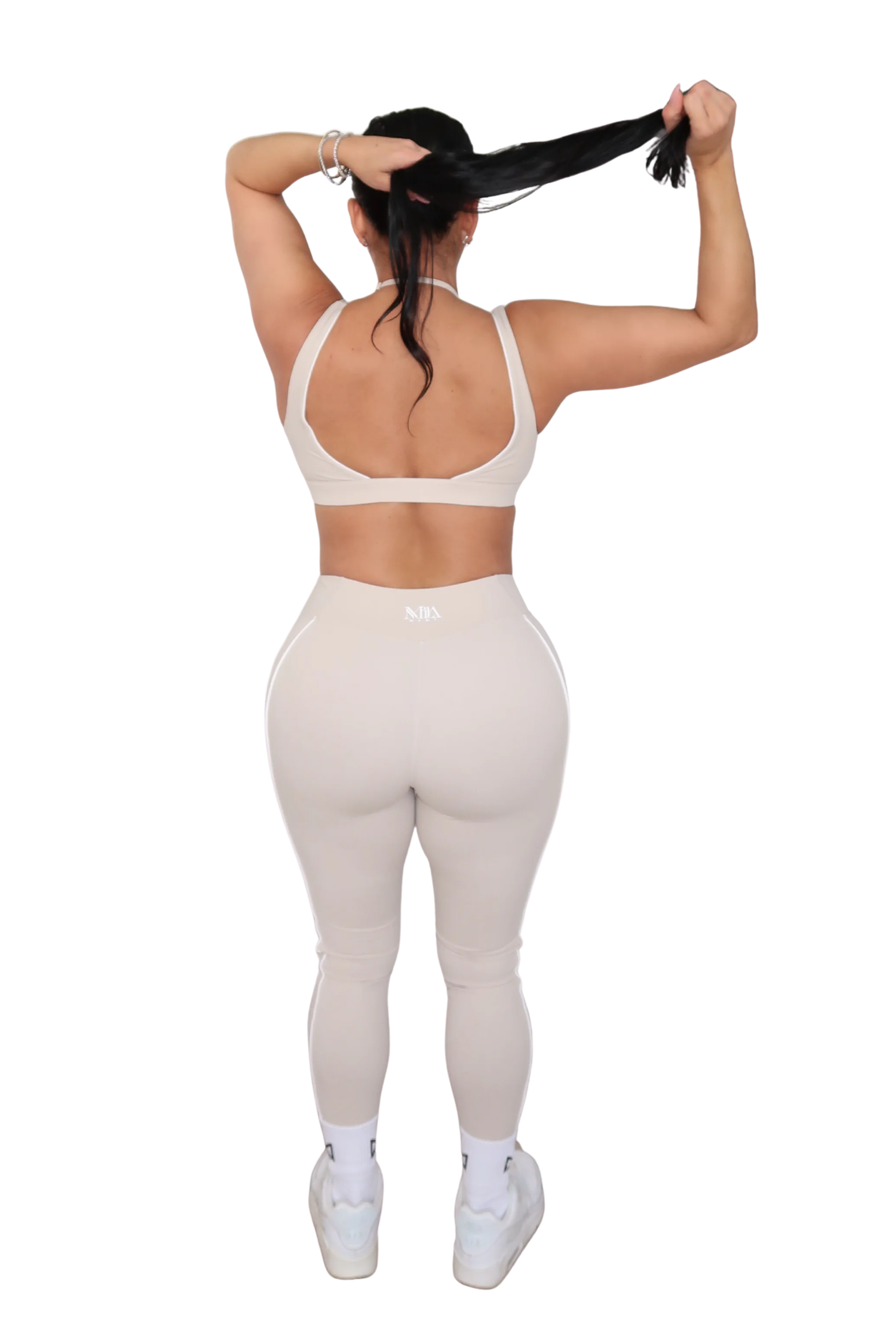 Person wearing a white sports bra and leggings set on a white background
