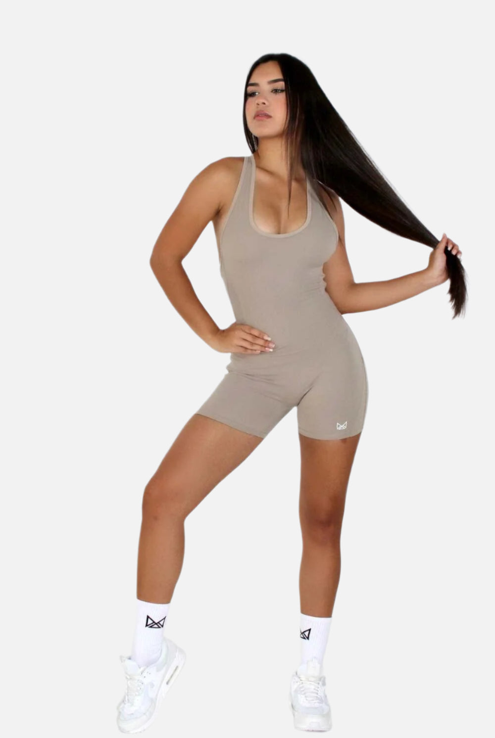 Women wearing a black MILA MVMT Sportswear One-Piece Gym Workout Romper Onesie - facing front grabbing her hair