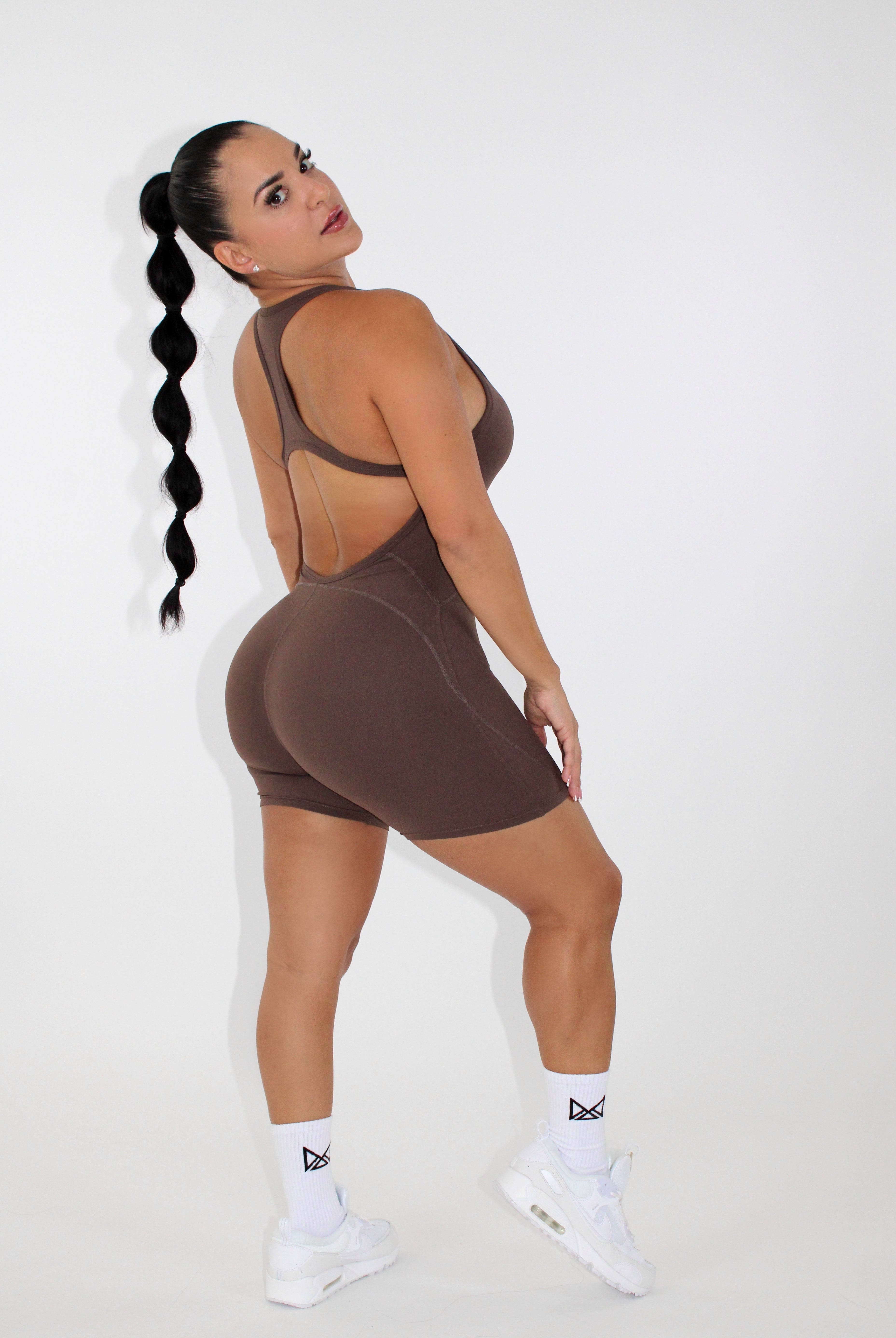 Women wearing a black MILA MVMT Sportswear One-Piece Gym Workout Romper Onesie - facing side looking at the camera