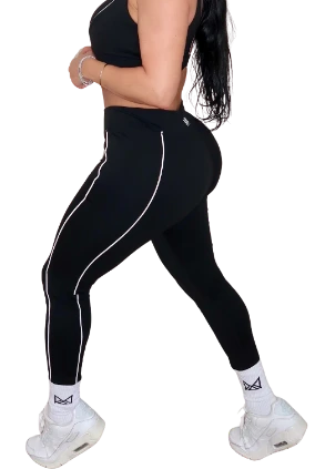 Woman wearing black athletic leggings with white stripes on a white background