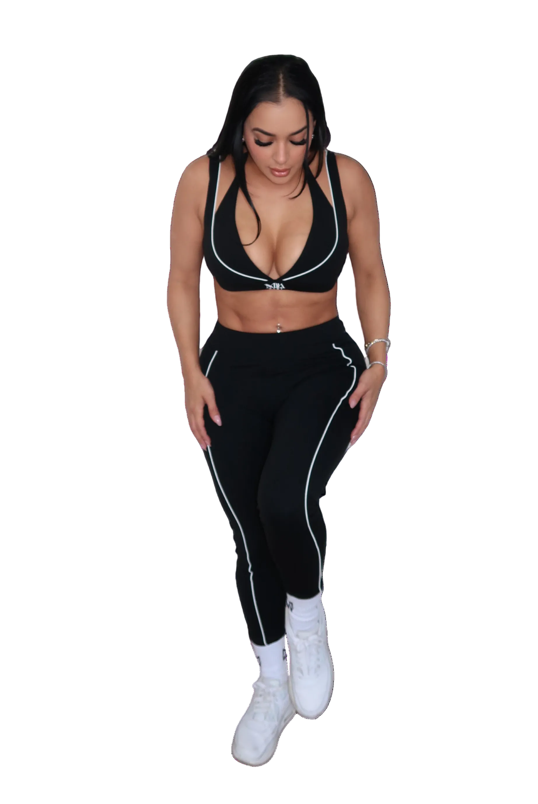 Woman wearing a black sports bra and leggings set on a white background