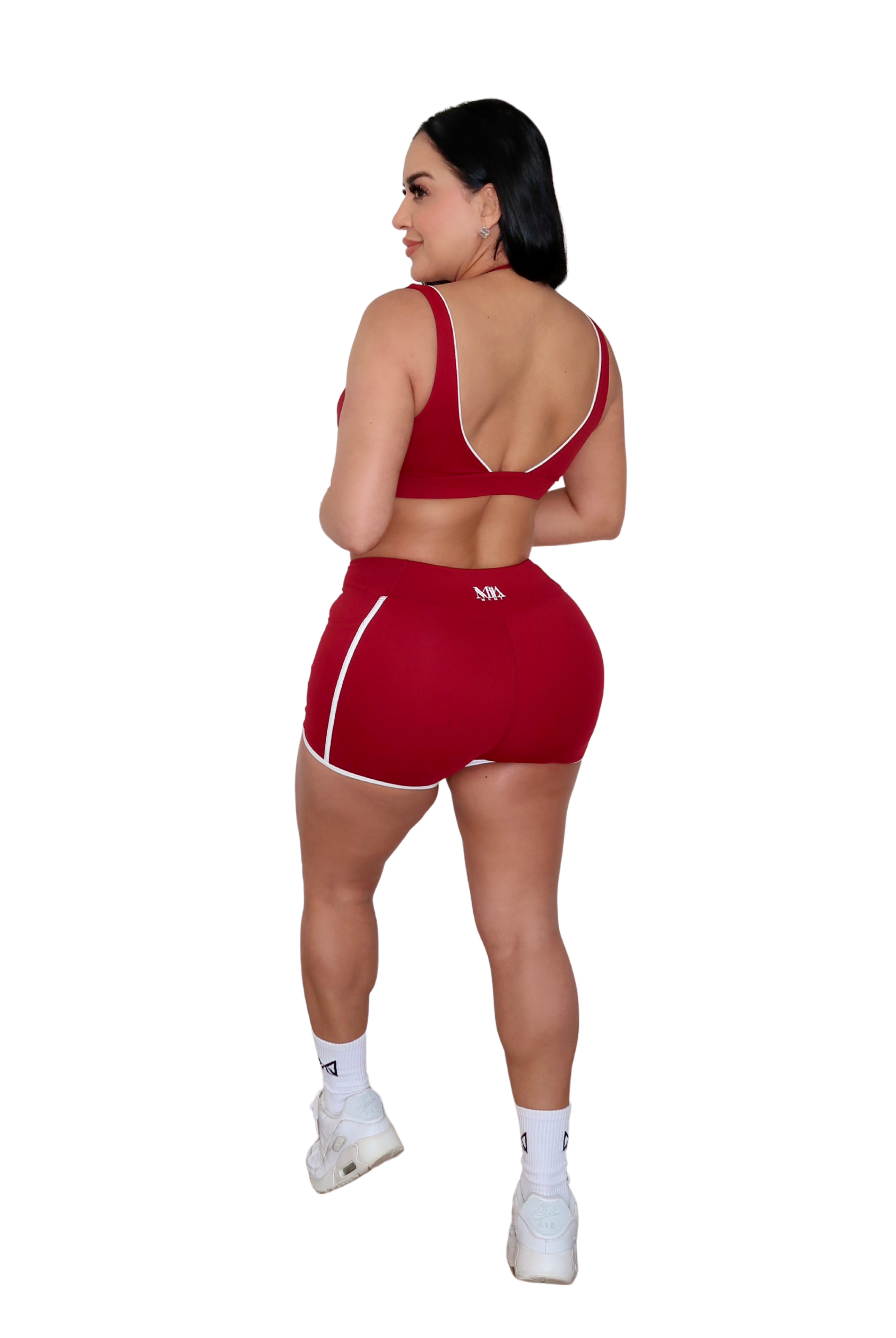 Woman wearing a red sports outfit with white accents on a white background