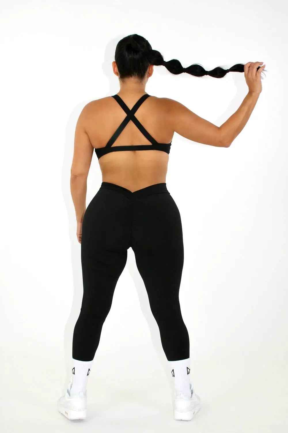Woman wearing black leggings and a black sports bra - back