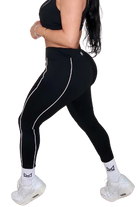 Woman wearing black athletic leggings with white stripes on a white background
