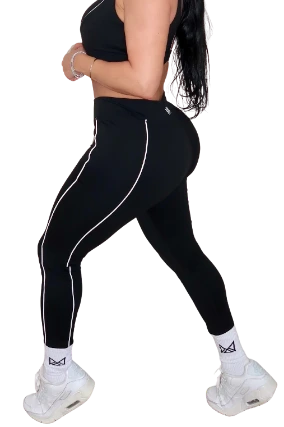 Woman wearing black athletic leggings with white stripes on a white background