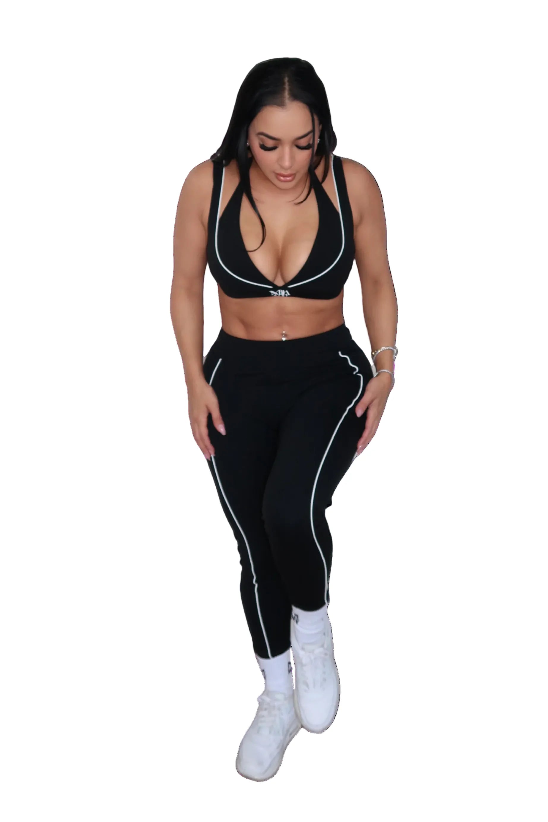 Woman wearing a black sports bra and leggings set on a white background