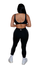 Person wearing a black sports bra and leggings set on a white background