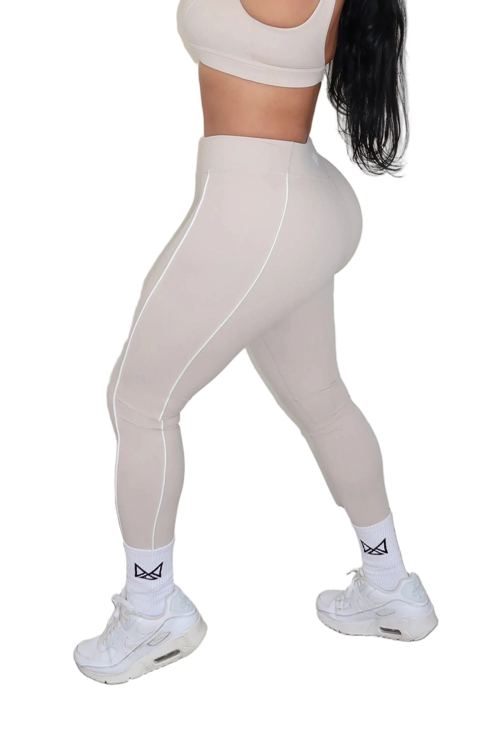Woman in beige athletic wear posing.
