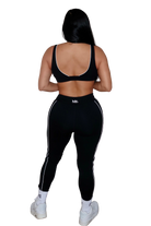Woman wearing a black sports bra and leggings, back view on a white background