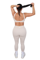 Person wearing a white sports bra and leggings set on a white background