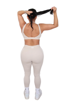Person wearing a white sports bra and leggings set on a white background