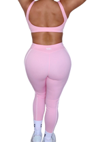 Back view of woman wearing petal pink leggings by MILA MVMT