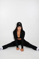 MILA MVMT Sportswear Gym Wear Workout Athleisure Crop Top Long Sleeve Black facing front sitting on the floor wearing ballcap