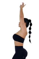 Woman wearing a black sports bra and shorts with white socks and shoes on a white background